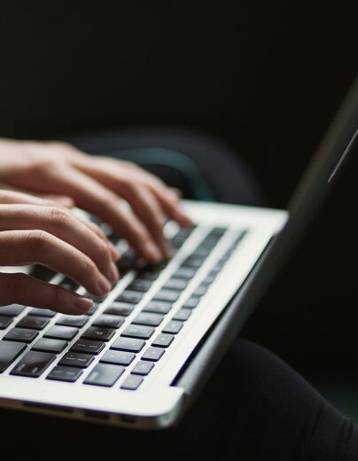 This image depicts a close-up of a person typing on a laptop keyboard.